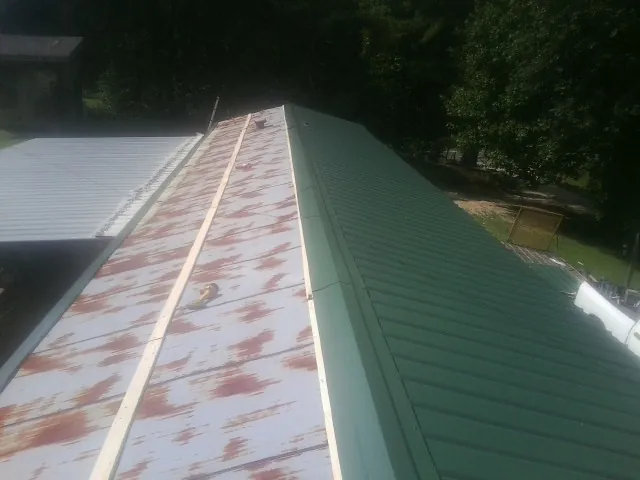 Old rusted panels beside newly installed green metal roofing — Wind Damage Roof Repair by Roofing Brothers in Norton