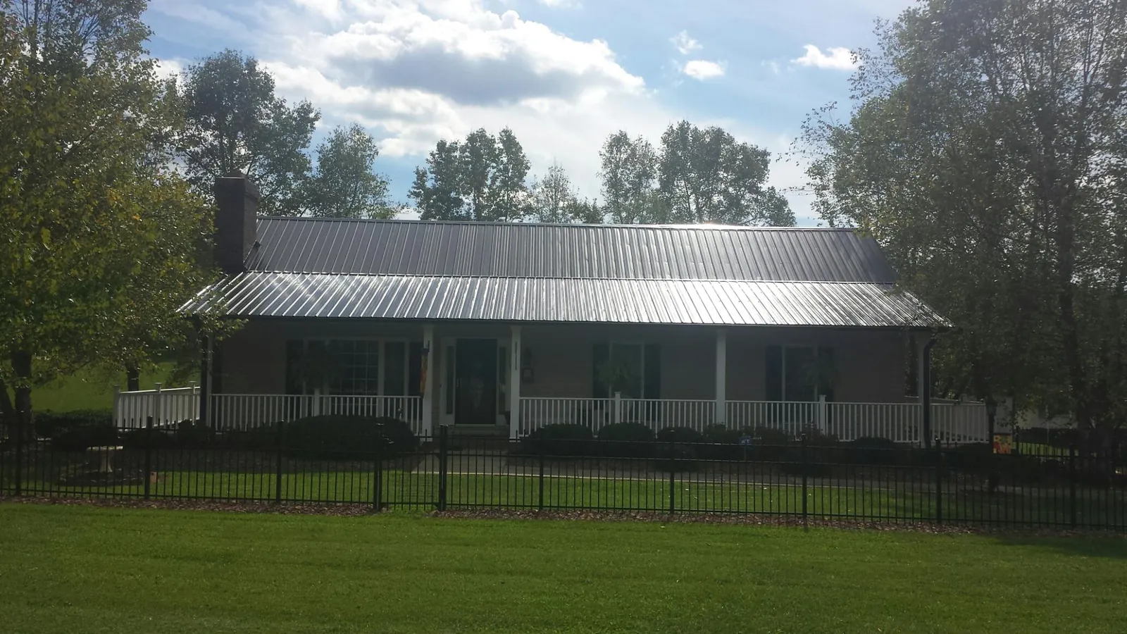Gray metal roof on a brick ranch with a full width front porch — Gutter Guard Installation work by our crew in Norton